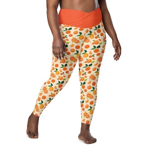 May include: Orange print leggings with a high waist and a wide orange waistband. The leggings have a white background with a repeating pattern of oranges and leaves.