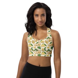 May include: A yellow sports bra with a repeating pattern of ginger root and leaves. The bra has a racerback style and is made of a stretchy, breathable fabric.