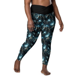 May include: Black leggings with a blue and gold galaxy print. The leggings have a wide waistband that wraps around the waist.