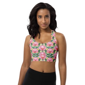 May include: A pink and green sports bra with a floral pattern. The bra has a racerback style and is made of a stretchy, breathable fabric.