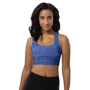 May include: A blue denim sports bra with a criss-cross back strap. The bra has a textured fabric and a scoop neck.