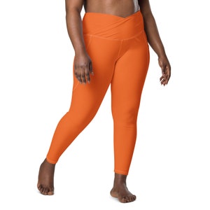 May include: A pair of orange high-waisted leggings with a criss-cross waistband.