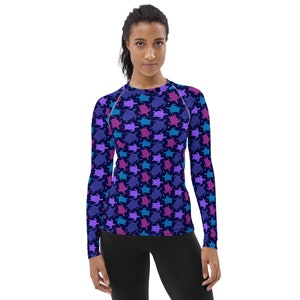 May include: A long-sleeved shirt with a dark blue background and a repeating pattern of colorful sea turtles. The turtles are in shades of pink, purple, and blue.