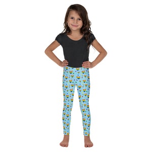 May include: A child wearing a pair of blue leggings with a rainbow heart pattern. The leggings are covered in a repeating pattern of rainbow hearts and colorful stars.