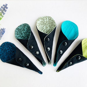 May include: Five fabric cones with different patterned fabric on the inside and black fabric on the outside. Each cone has a black button on the outside.