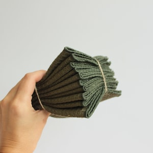 May include: A stack of dark green kitchen towels folded and tied with twine.