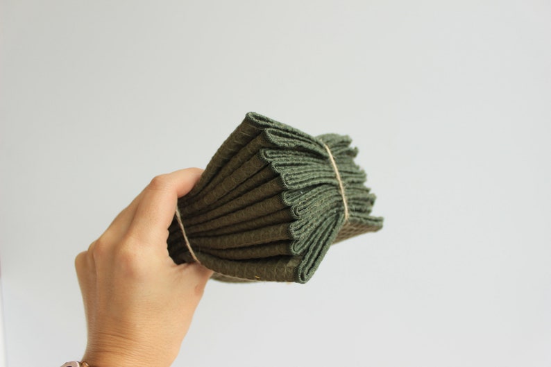May include: A stack of dark green kitchen towels folded and tied with twine.