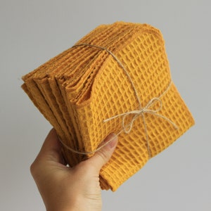 May include: A stack of yellow waffle weave kitchen towels tied with twine.
