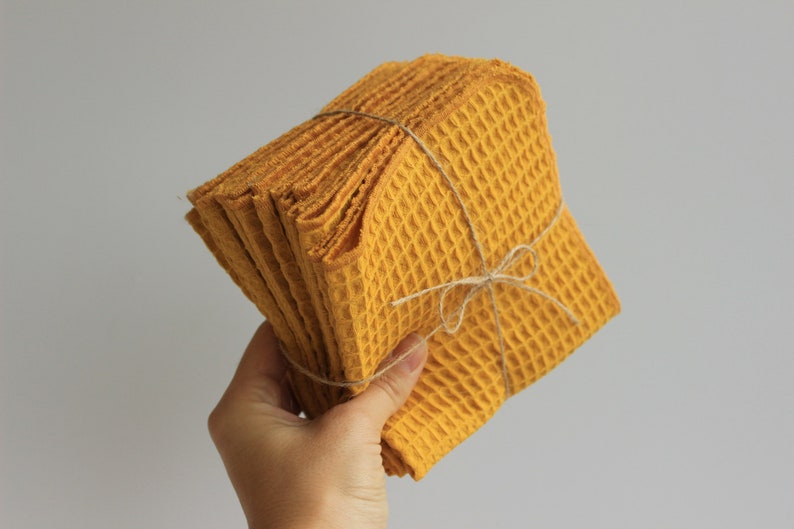 May include: A stack of yellow waffle weave kitchen towels tied with twine.