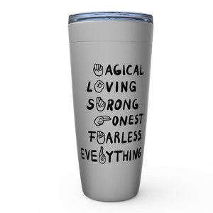 K&ouml;nnte beinhalten: Ein grauer Edelstahlbecher mit einem schwarzen Deckel und einem Design, das "MAGICAL LOVING STRONG HONEST FEARLESS EVERYTHING" mit Handzeichen f&uuml;r jedes Wort sagt.