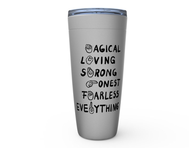K&ouml;nnte beinhalten: Ein grauer Edelstahlbecher mit einem schwarzen Deckel und einem Design, das "MAGICAL LOVING STRONG HONEST FEARLESS EVERYTHING" mit Handzeichen f&uuml;r jedes Wort sagt.