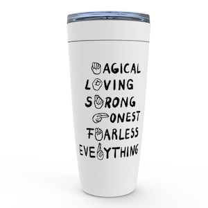 K&ouml;nnte beinhalten: Wei&szlig;e Reisebecher mit schwarzem Text und Geb&auml;rdensprachsymbolen, die "Magical Loving Strong Honest Fearless Everything" lauten.