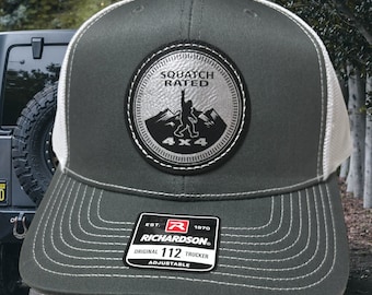 May include: A gray and white trucker hat with a black and silver patch that says "Squatch Rated 4x4" and a Bigfoot figure. The hat has a white mesh back and a black label that says "Richardson 112 Original Trucker Adjustable".