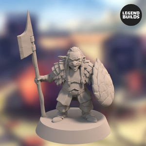 Puede incluir: Figura detallada de un guerrero de fantasía, sosteniendo una gran hacha y un escudo. La figura tiene una expresión feroz, cabello trenzado y está vestida con armadura. La base es una plataforma redonda simple. El logotipo de Legend Builds está en la esquina superior derecha.