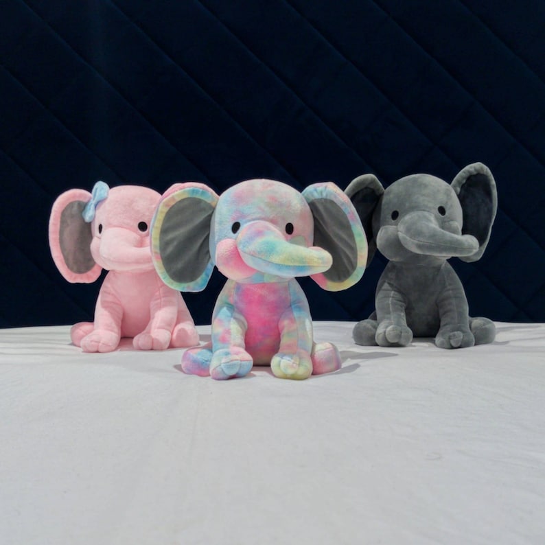May include: Three plush elephant toys. One is pink, one is gray, and one is rainbow colored.