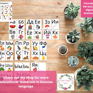 May include: Printable Russian alphabet flashcards with colorful illustrations. Each card features a letter of the Russian alphabet with a corresponding image. The cards are arranged in rows on a wooden surface with potted succulents.