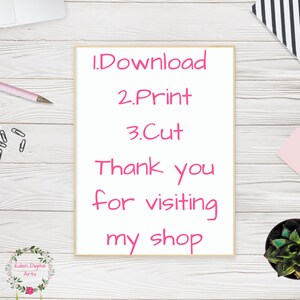 May include: A framed white print with pink text that reads "1. Download, 2. Print, 3. Cut, Thank you for visiting my shop." The print is on a white wooden surface with a pink pen, paperclips, and a small plant.