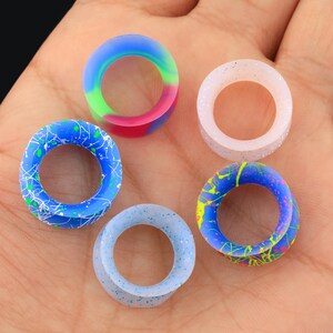 May include: Five silicone ear gauges in different colors and patterns. The gauges are in a variety of colors, including blue, white, pink, and green. The gauges are all circular and have a hole in the center.