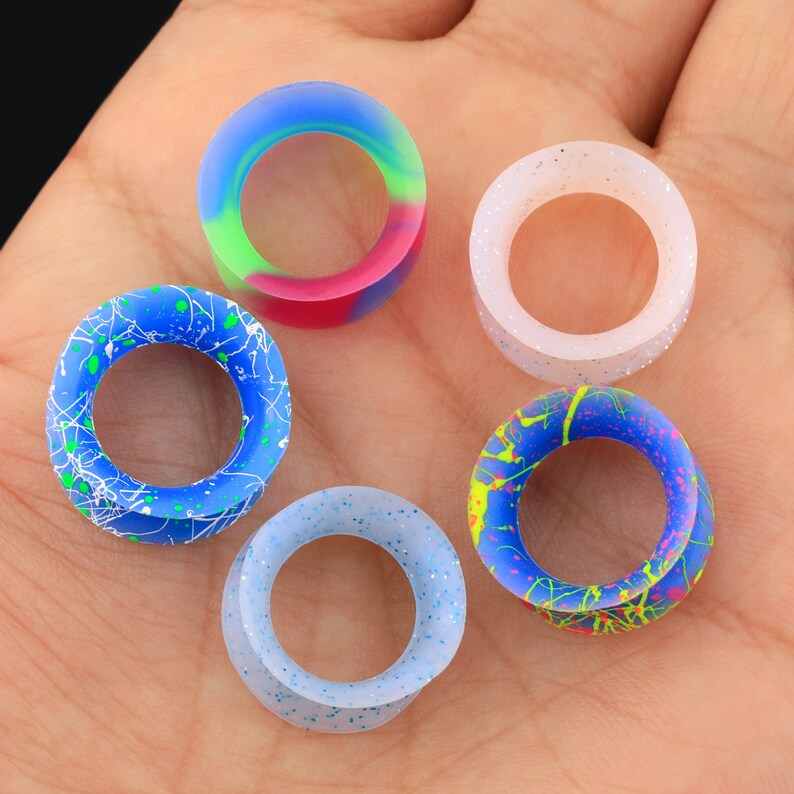 May include: Five silicone ear gauges in different colors and patterns. The gauges are in a variety of colors, including blue, white, pink, and green. The gauges are all circular and have a hole in the center.