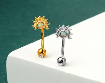 May include: Two belly button rings with a sunburst design and an opal stone. One ring is gold and the other is silver.