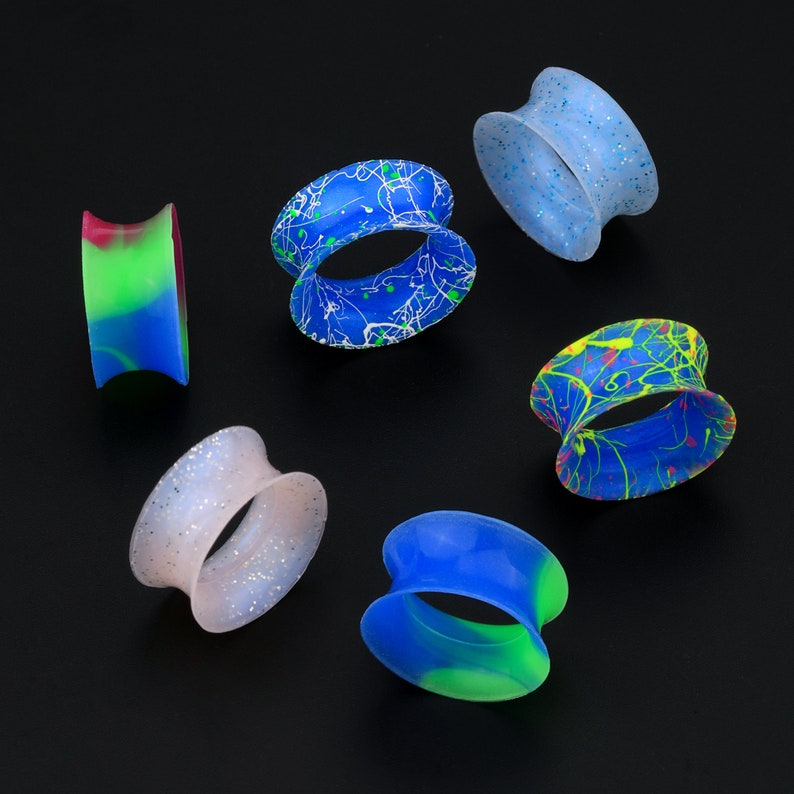 May include: Assortment of six silicone ear gauges in various colors and patterns, including blue, green, white, and black.