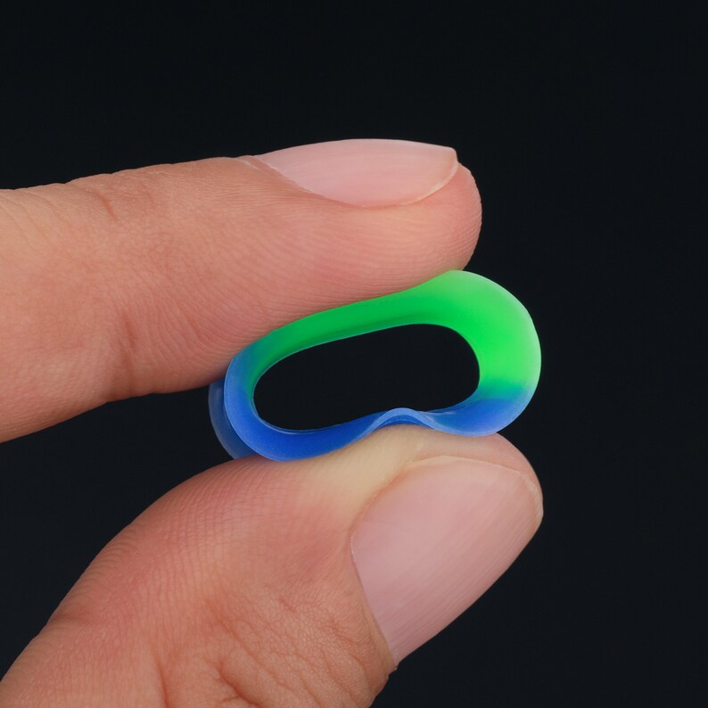 May include: A green and blue ombre silicone ring. The ring is flexible and has a smooth finish.