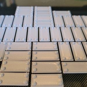 May include: A collection of 25 gray plastic tiles with a textured surface and raised edges. The tiles are arranged in a staggered pattern.