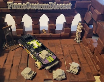 Pode incluir: Um carro de brinquedo preto e verde com um design de caveira e ossos cruzados brancos. O carro está em um conjunto de jogo marrom e cinza com uma guilhotina, uma caveira e uma figura de esqueleto. O conjunto de jogo tem as palavras "Films Custom Diecast" no topo.