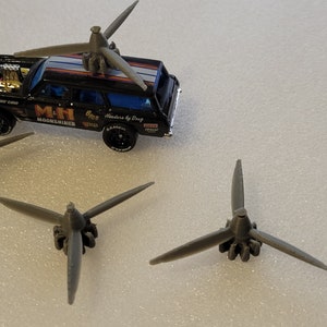 May include: Four gray plastic propellers with three blades each. The propellers are on a white surface.