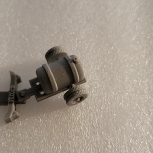 May include: A gray plastic model of a small tanker truck with four wheels.