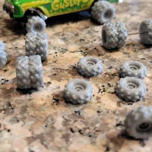 8 Dual and 8 Single Mud Grip Tires with hole in center 1/64 scale. Silver 3d printed. 16 items all together.