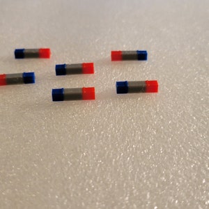 May include: Six small, cylindrical magnets with blue and red ends. The magnets are arranged in two rows of three.