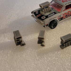 May include: Four gray plastic model car engine blocks. The engine blocks are detailed with multiple parts and are approximately 2 inches in length.