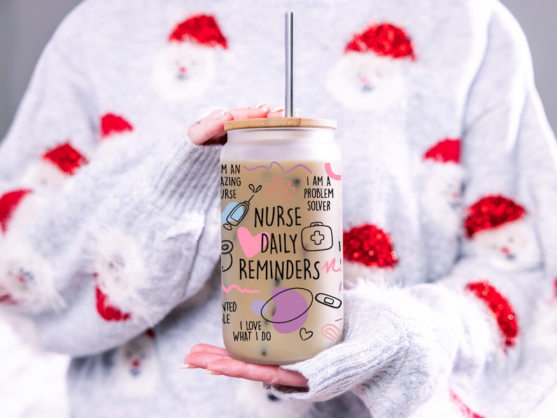 May include: A white glass tumbler with a bamboo lid and a straw. The tumbler has a pink and black design with the text "Nurse Daily Reminders" and other related phrases.