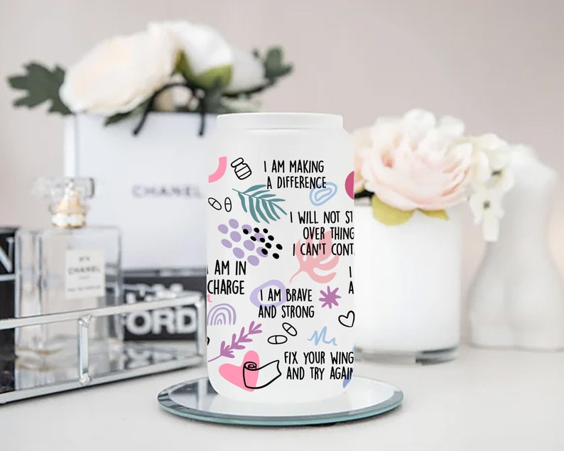 May include: White tumbler with a colorful design and inspirational quotes. The quotes include "I am making a difference", "I will not stop", "I am in charge", "I am brave and strong", and "Fix your wing and try again".