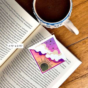 May include: A square bookmark measuring 2.75 inches by 2.75 inches featuring a gradient design transitioning from a dark purple starry night sky at the top to a warm orange sunrise at the bottom, accented with white die-cut clouds.
