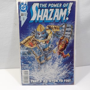 May include: Comic book cover for "The Power of Shazam!" featuring a robot and two figures in action against a blue background. The cover includes the DC Comics logo and the text "THAT'S MR. ATOM TO YOU!"