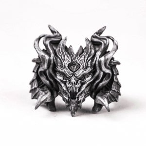 May include: A silver-colored, detailed, 3D printed dragon head sculpture with a fierce expression. The dragon has horns, fangs, and a textured, scaly body.