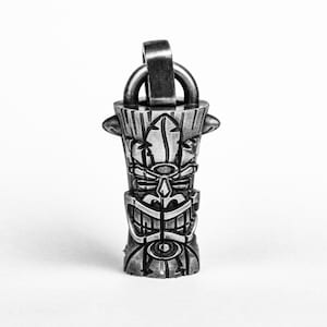 May include: A silver tiki pendant with a detailed carved face and a loop for attaching a chain.