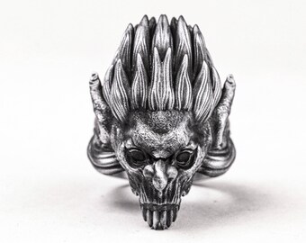 May include: A silver ring with a detailed design of a demonic creature with a spiky crown and sharp teeth.
