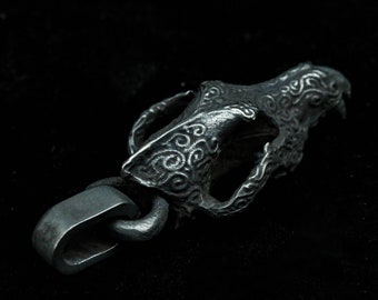 May include: A silver pendant in the shape of a wolf skull with intricate swirling designs. The pendant has a silver chain attached to it.