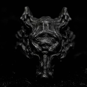 May include: A black, detailed, sculpted wolf head with a textured surface.