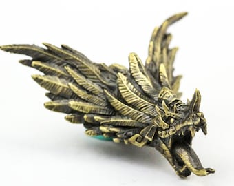 Puede incluir: Una escultura de bronce detallada de un dragón alado con una expresión feroz. Las alas del dragón están extendidas y su boca está abierta en un rugido. La escultura está hecha con detalles intrincados, incluyendo plumas en las alas y escamas en el cuerpo.