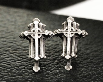 May include: A pair of silver cross earrings. Each earring features a detailed design of four crosses layered on top of each other.