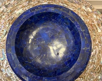 May include: A round, blue lapis lazuli bowl set in a circular, multi-layered, iridescent mother of pearl base.