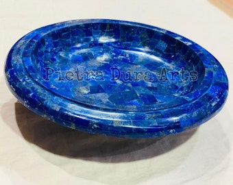May include: Oval-shaped, mosaic-style dish in deep blue. The dish is made of small, irregularly shaped pieces, creating a textured surface. The text "Pietra Dura Arts" is visible on the dish.