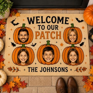 May include: A rectangular tan doormat featuring the text WELCOME TO OUR PATCH and THE JOHNSONS. The design includes five orange pumpkins, each displaying a different person's face, surrounded by black bat silhouettes and small star accents.