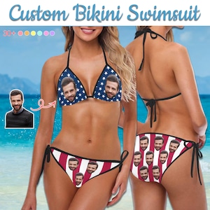 May include: Custom bikini swimsuit with a face print on the top and bottom. The top is navy blue with white stars, and the bottom has red and white stripes. The swimsuit has black ties.