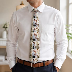May include: A necktie featuring a repeating vertical pattern of a couple standing together in a natural outdoor setting. The tie is worn over a crisp white button-down shirt with a pointed collar and is secured with a brown leather belt.