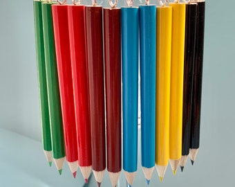 May include: A set of eight colorful pencil earrings, each with a silver hook. The pencils are green, red, maroon, blue, light blue, yellow, and black.
